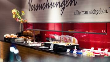 A buffet area with various food items and a sign that reads "Versuchungen" and "should man nachgeben."