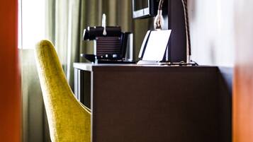 Una habitación de hotel con escritorio, una silla, televisor y lámpara.