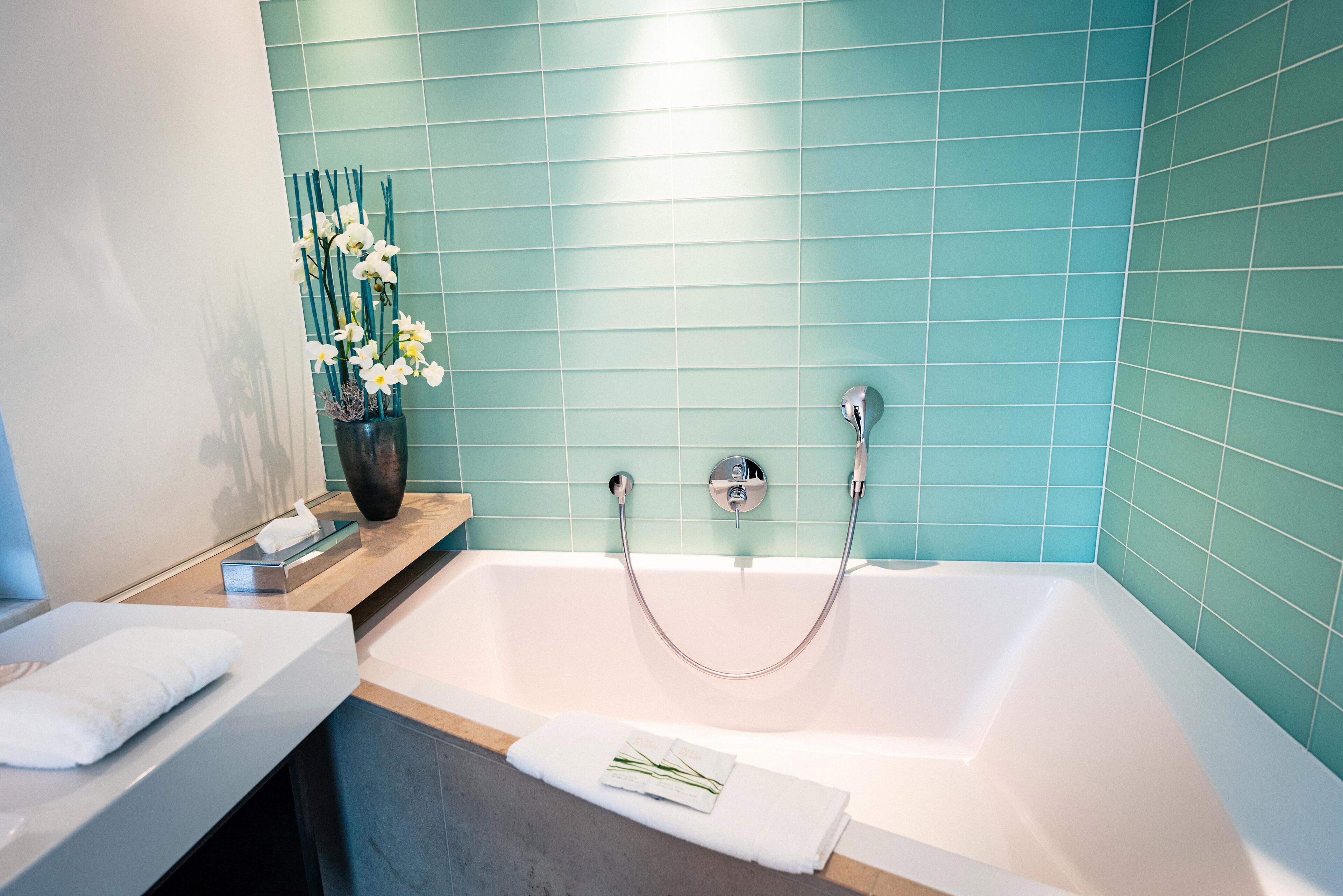A modern bathroom with a bathtub, a sink, and a vase with flowers.