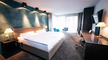 A hotel room with a large bed, bedside lamps, a desk, a chair, and a TV.