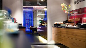 A reception area with a wooden counter, a menu board, and a flower vase. - Hotel Der Blaue Reiter Design- & Tagungshotel (Karlsruhe)