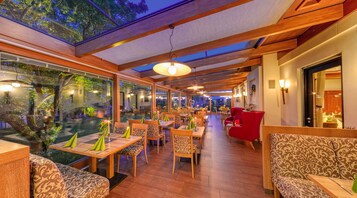 A restaurant with wooden furniture, large windows, and a high ceiling with skylights.