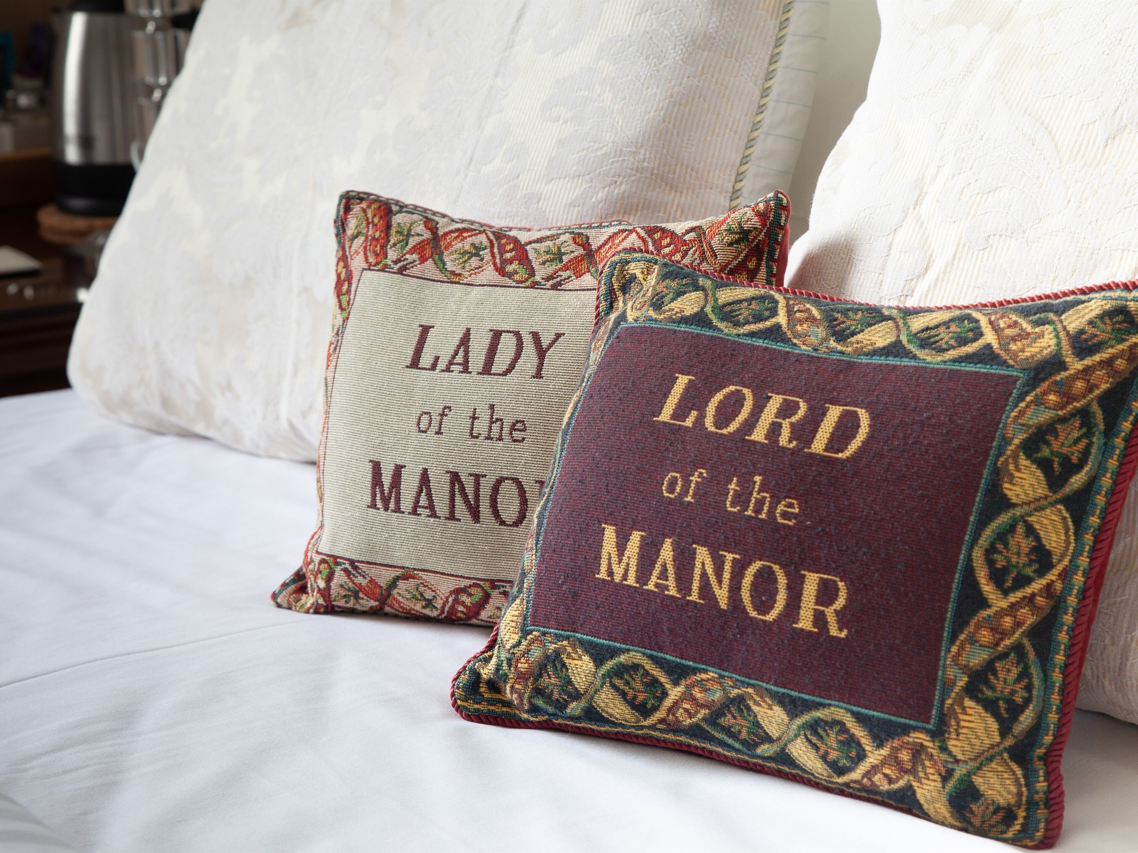 Two decorative pillows with embroidered text on a bed.