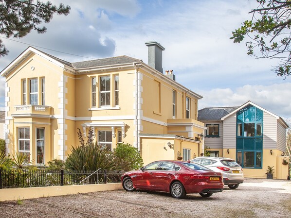A yellow building with a red car parked in front.