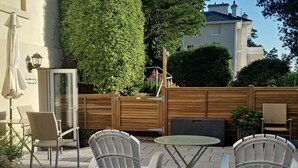 An outdoor patio with two white chairs, a small round table, and a wooden fence. - Court Prior Boutique B&B and Apartment (Torquay)