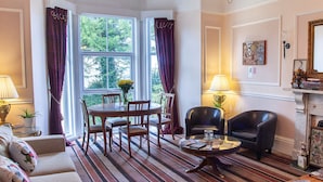 A well-furnished living room with a round dining table, two chairs, a sofa, a coffee table, and a fireplace. - Court Prior Boutique B&B and Apartment (Torquay)