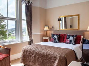 A hotel room with a large bed, a nightstand, a lamp, a mirror, and a view of the outside. - Court Prior Boutique B&B and Apartment (Torquay)