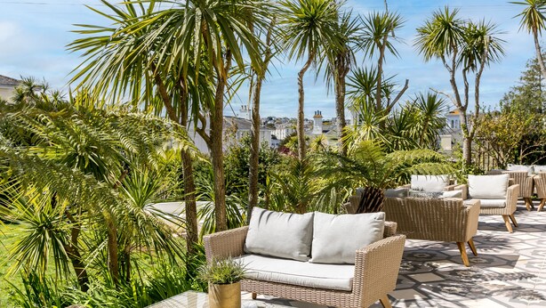 An outdoor seating area with wicker furniture and potted plants. - The Torcroft (Torquay)
