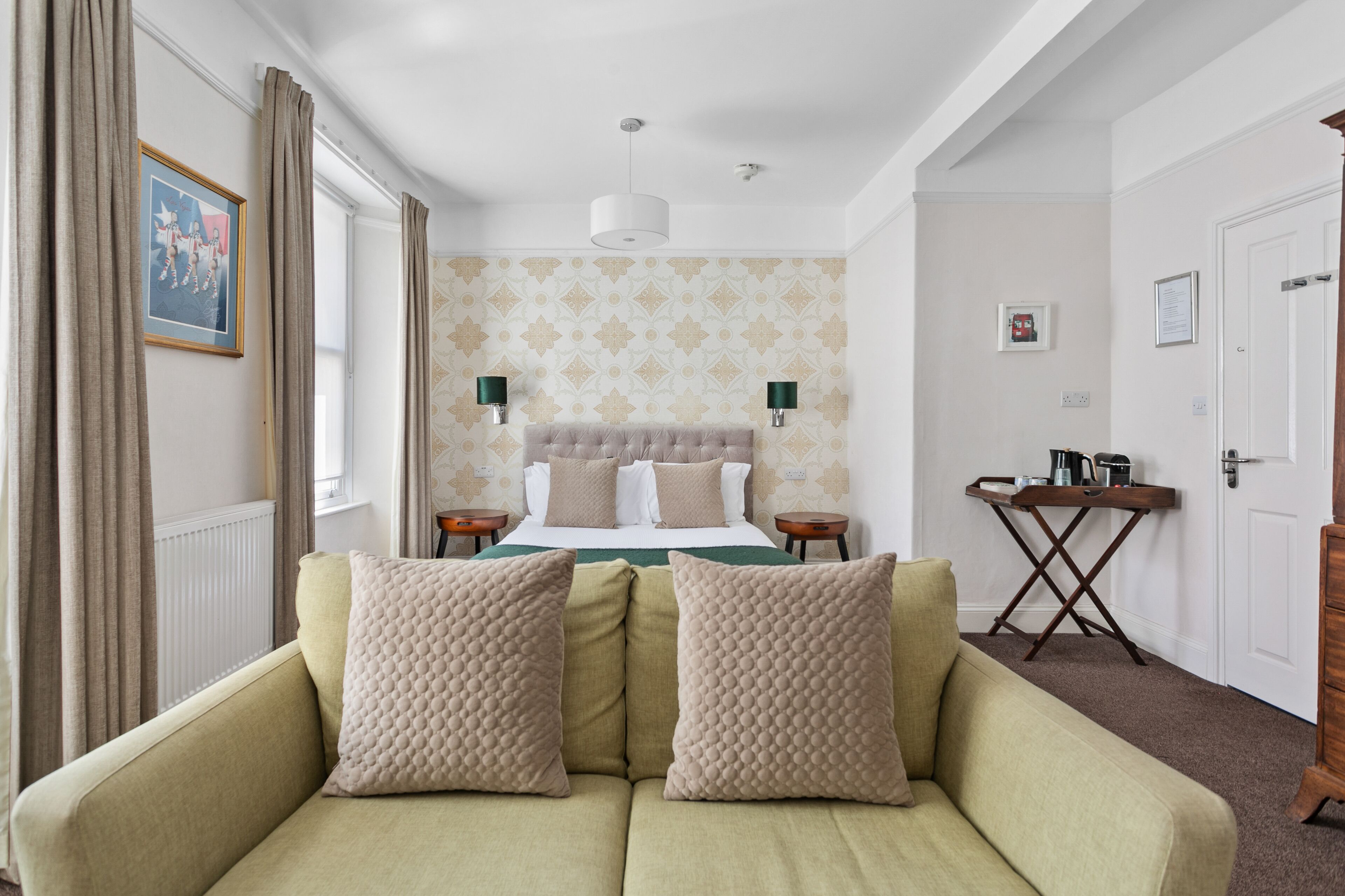 Una habitación de hotel con una cama, un sofá, una mesita y una puerta.