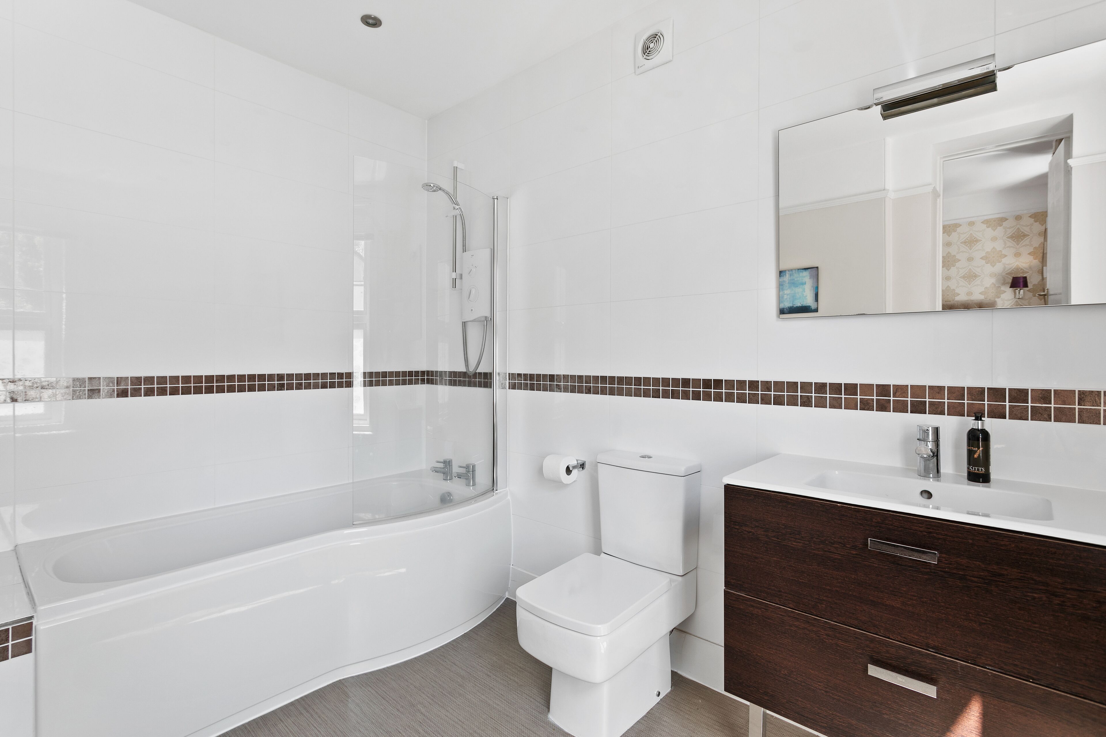 A modern bathroom with a bathtub, toilet, and vanity with a mirror.