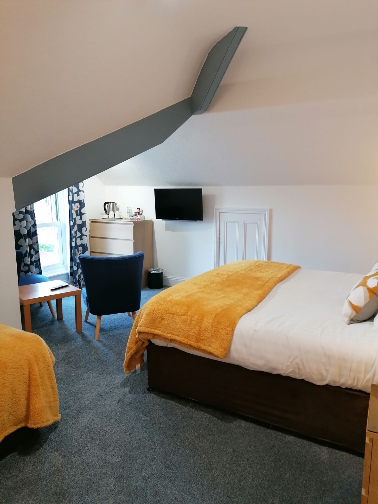 A bedroom with a bed, a desk, a chair, and a TV.