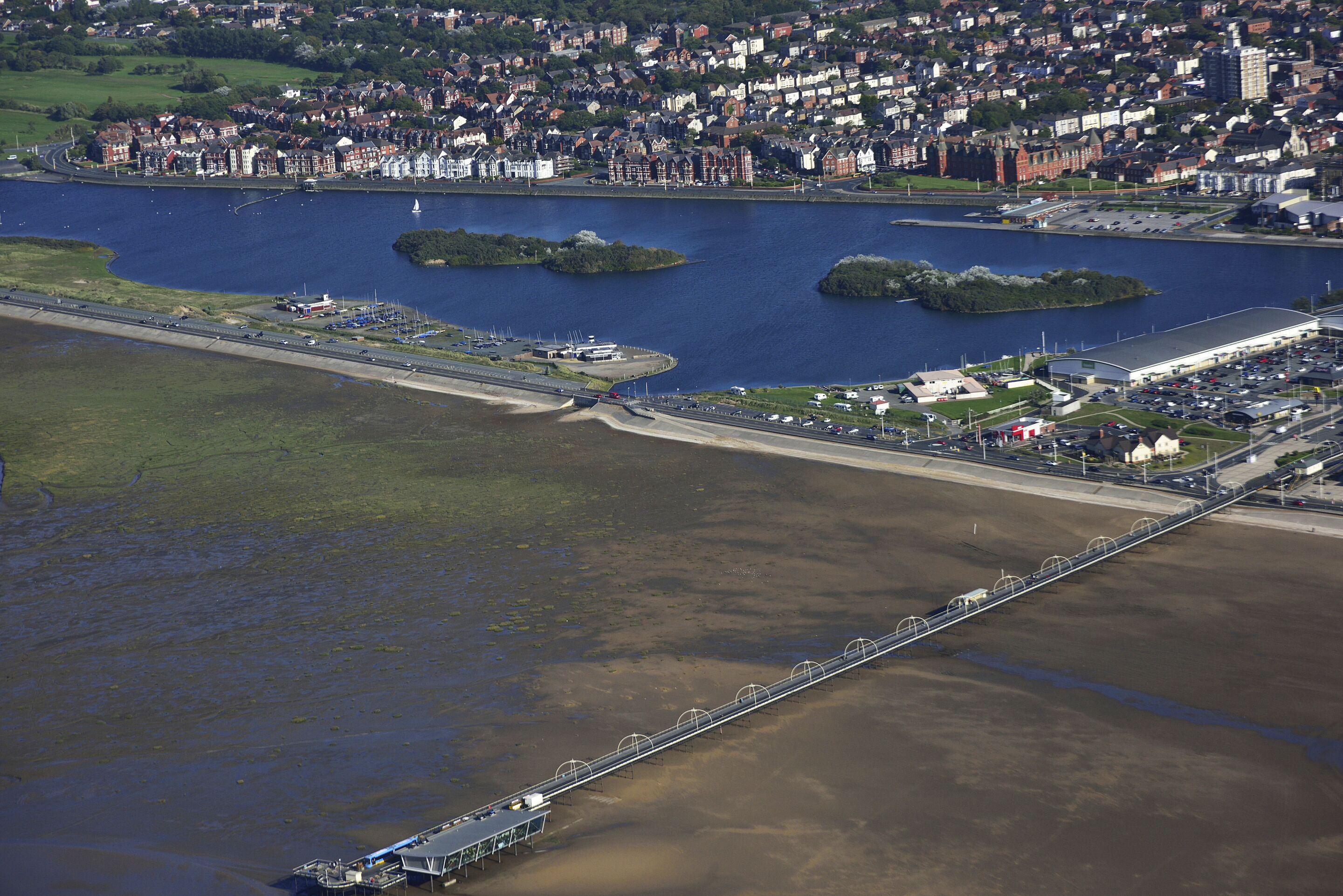 An aerial view of a coastal city with a bridge, a marina, and residential areas.