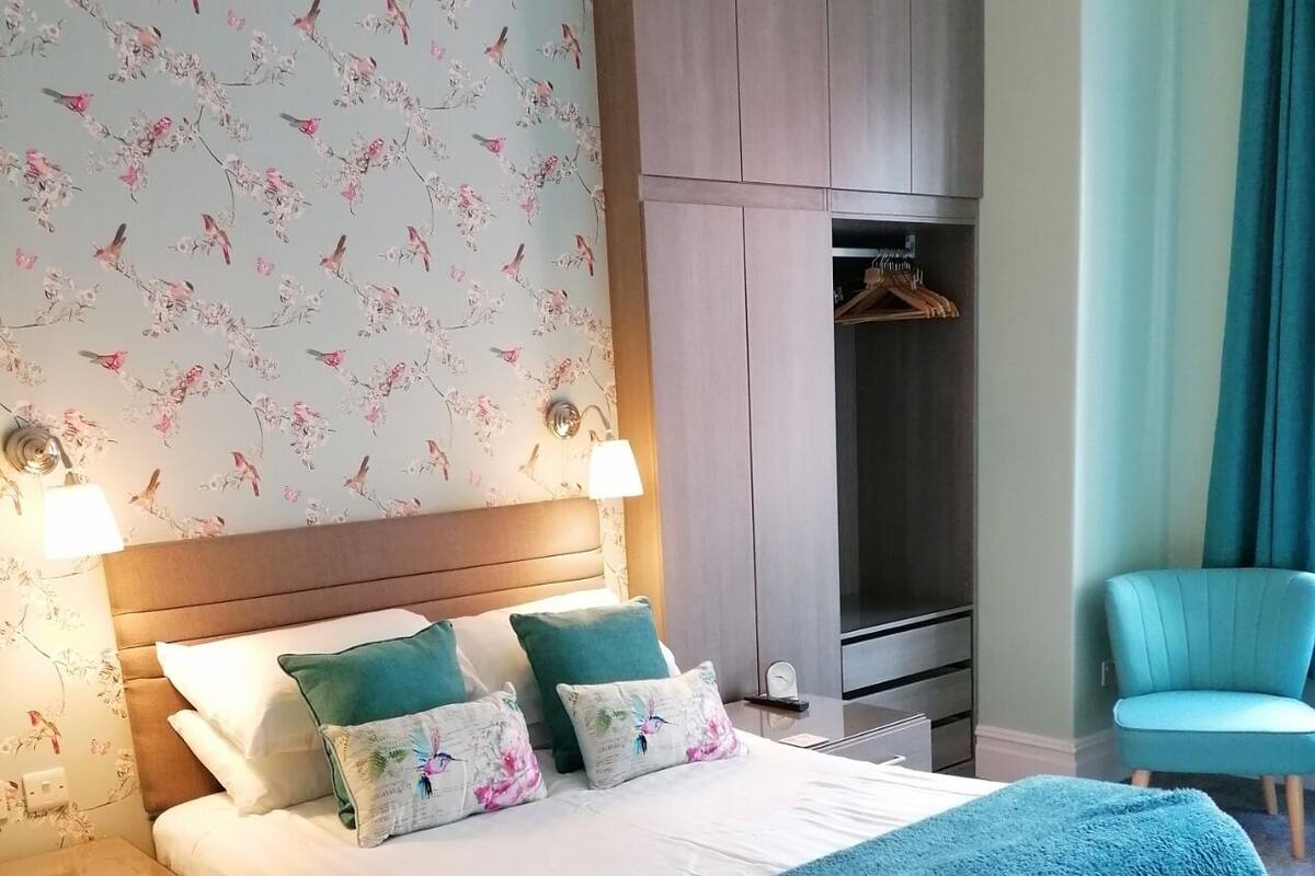 Quarto bem organizado com cama, abajures, guarda-roupa e uma cadeira.