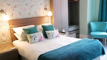 A neatly arranged bedroom with a bed, bedside lamps, a wardrobe, and a chair.