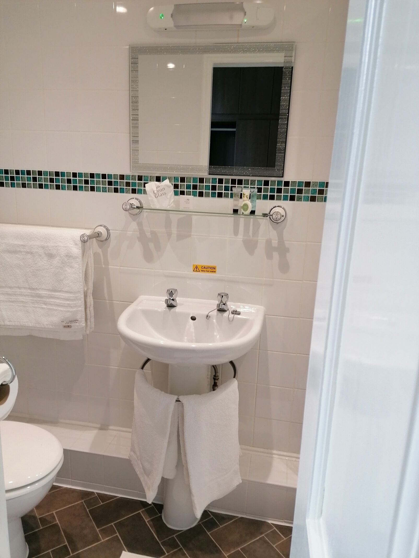 Une salle de bain avec un lavabo blanc, un miroir au-dessus et un porte-serviettes.
