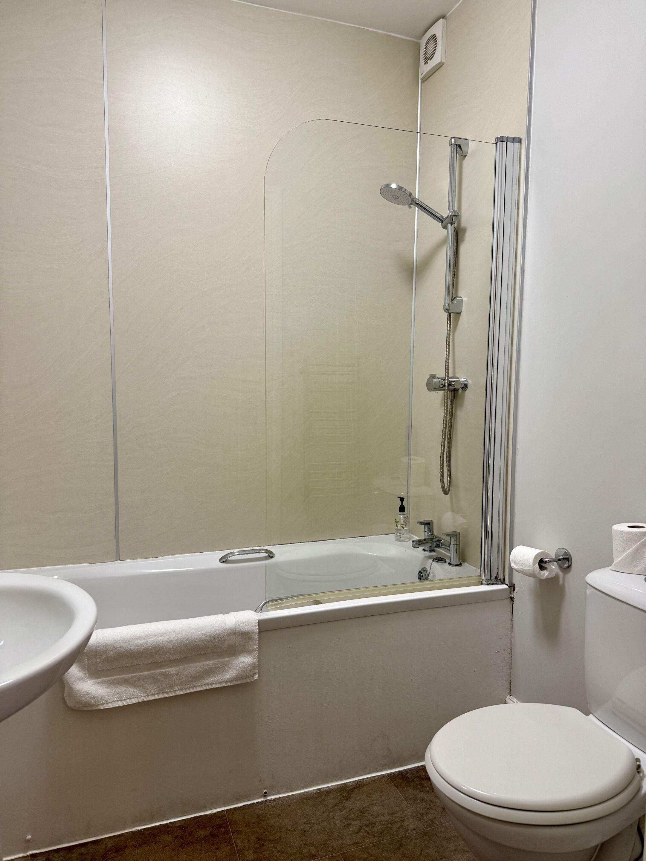 A bathroom with a bathtub, sink, toilet, and a glass shower enclosure.