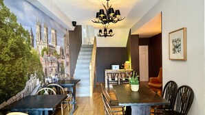 A dining area with a mural of a cityscape, a chandelier, and a staircase leading to another level. - The Crescent Guest House (York)