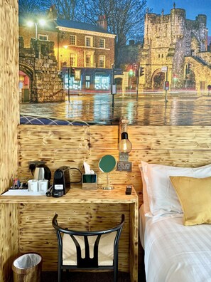 A room with a bed, a wooden desk, a chair, a small table with a tissue box, a coffee maker, and a mirror. - The Crescent Guest House (York)