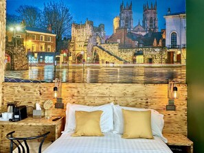 A hotel room with a bed, bedside tables, and a view of a historic cityscape with a river.
