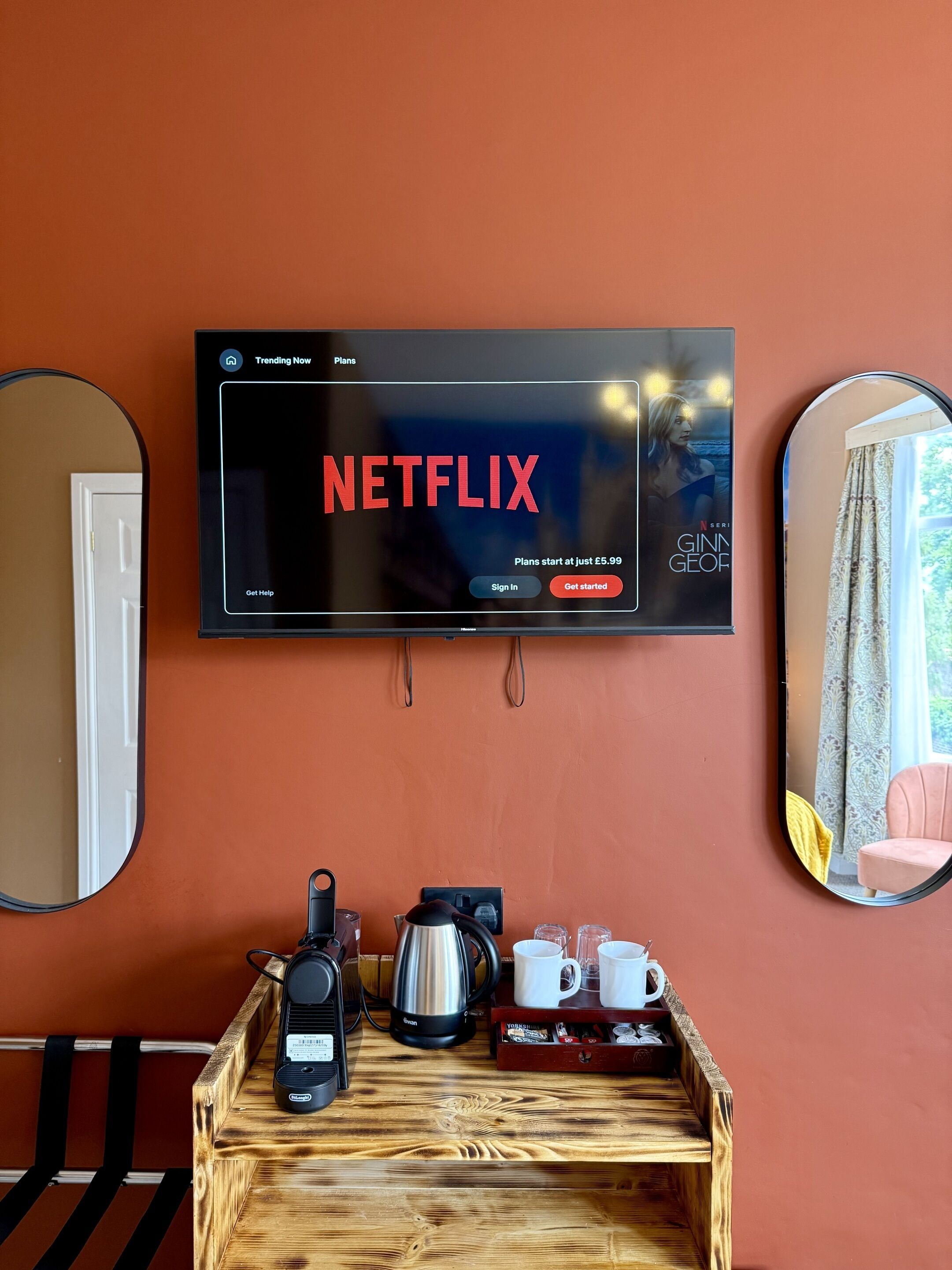 A television mounted on a wall displaying the Netflix interface with options to get help, sign in, and get started.