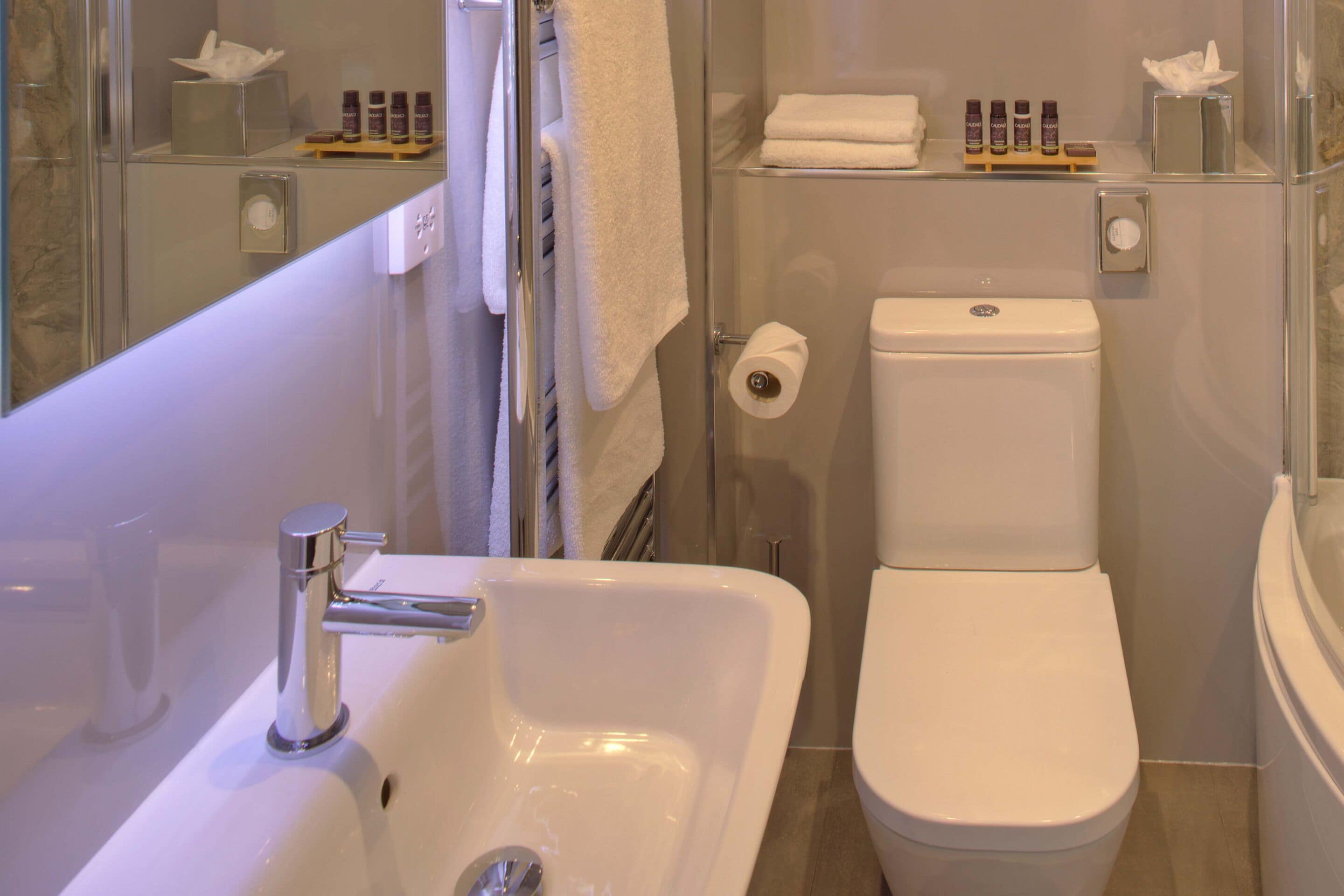 A modern bathroom with a white sink, toilet, and glass shower enclosure.