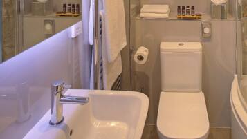 A modern bathroom with a white sink, toilet, and glass shower enclosure.
