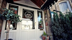 A building entrance with a white door, a sign reading "The Farthings," and potted plants outside. - The Farthings Guest House (York)