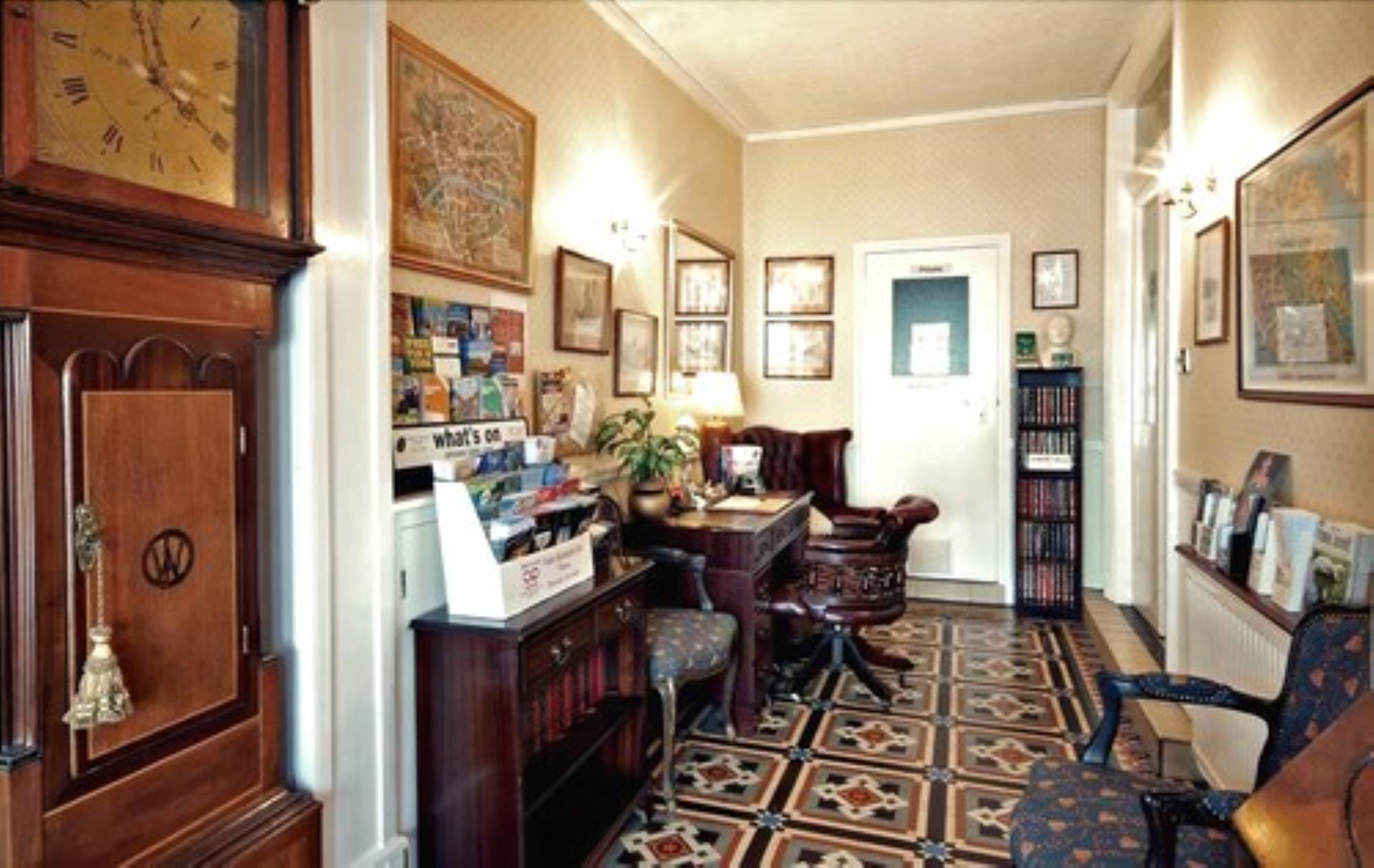 A cozy living room with a wooden cabinet, a desk, and a patterned floor.