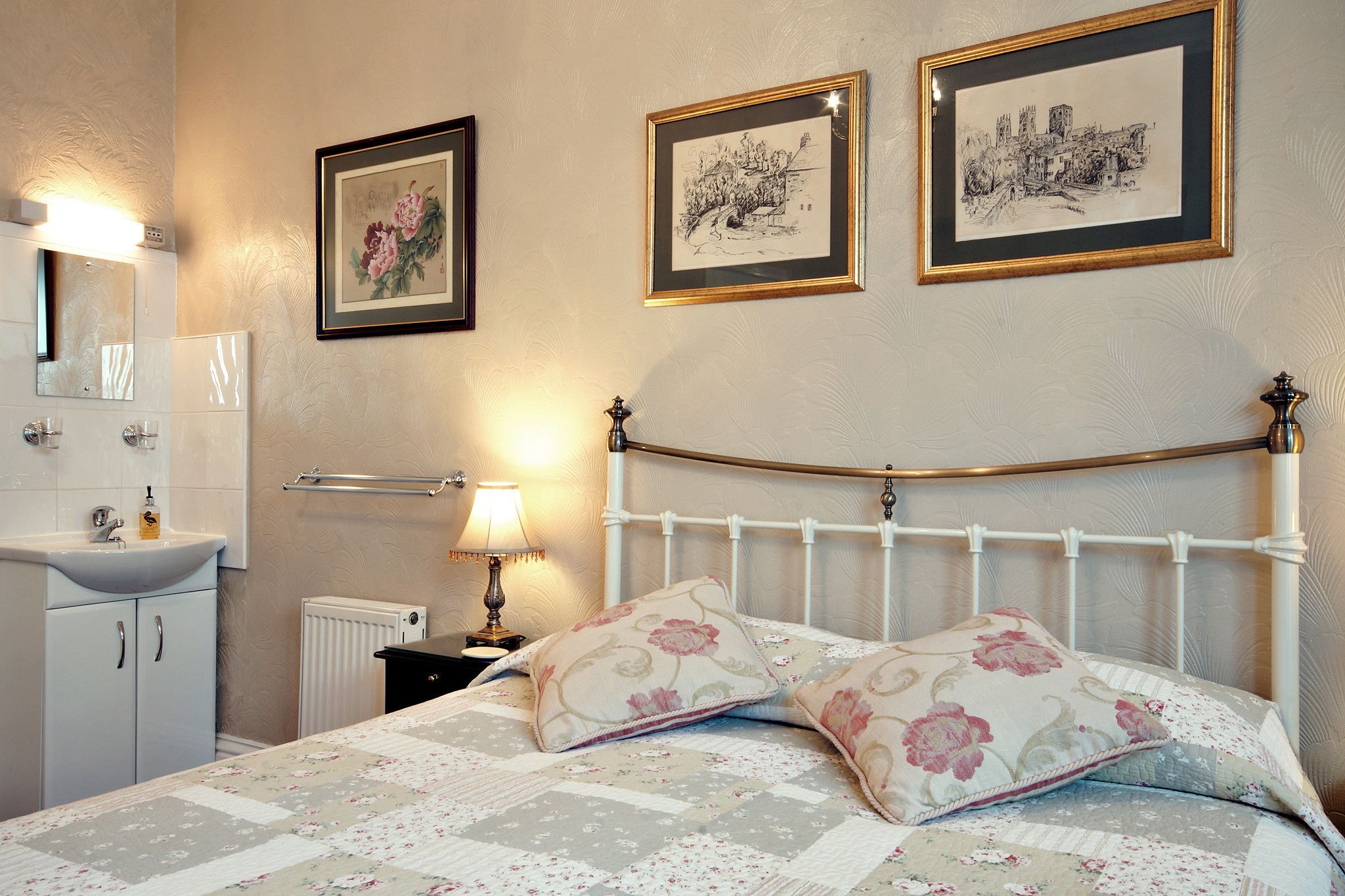 Une chambre à coucher comprenant un lit, une table de chevet, une lampe, un radiateur, un miroir et un tableau encadré accroché au mur.