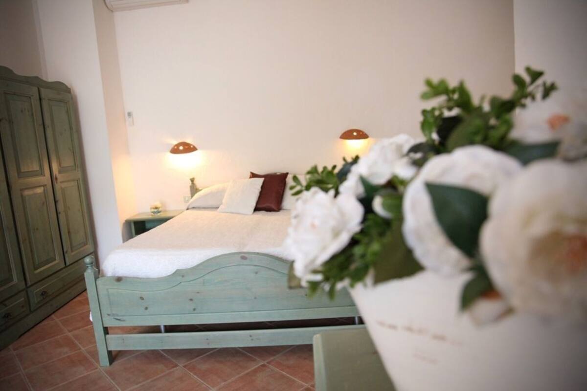 A bedroom with a bed, nightstands, and a green wardrobe.
