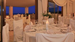 A formal dining setup with tables set for multiple guests, featuring white tablecloths, glassware, and candles. - Hotel Micalosu (Arzachena)
