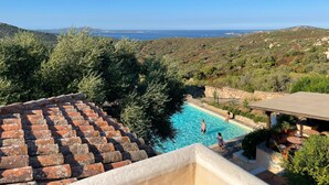 A pool with a view of the sea and hills, surrounded by greenery and a stone wall. - Hotel Micalosu (Arzachena)