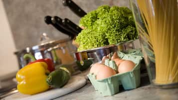 A kitchen counter with vegetables, eggs, and pasta.