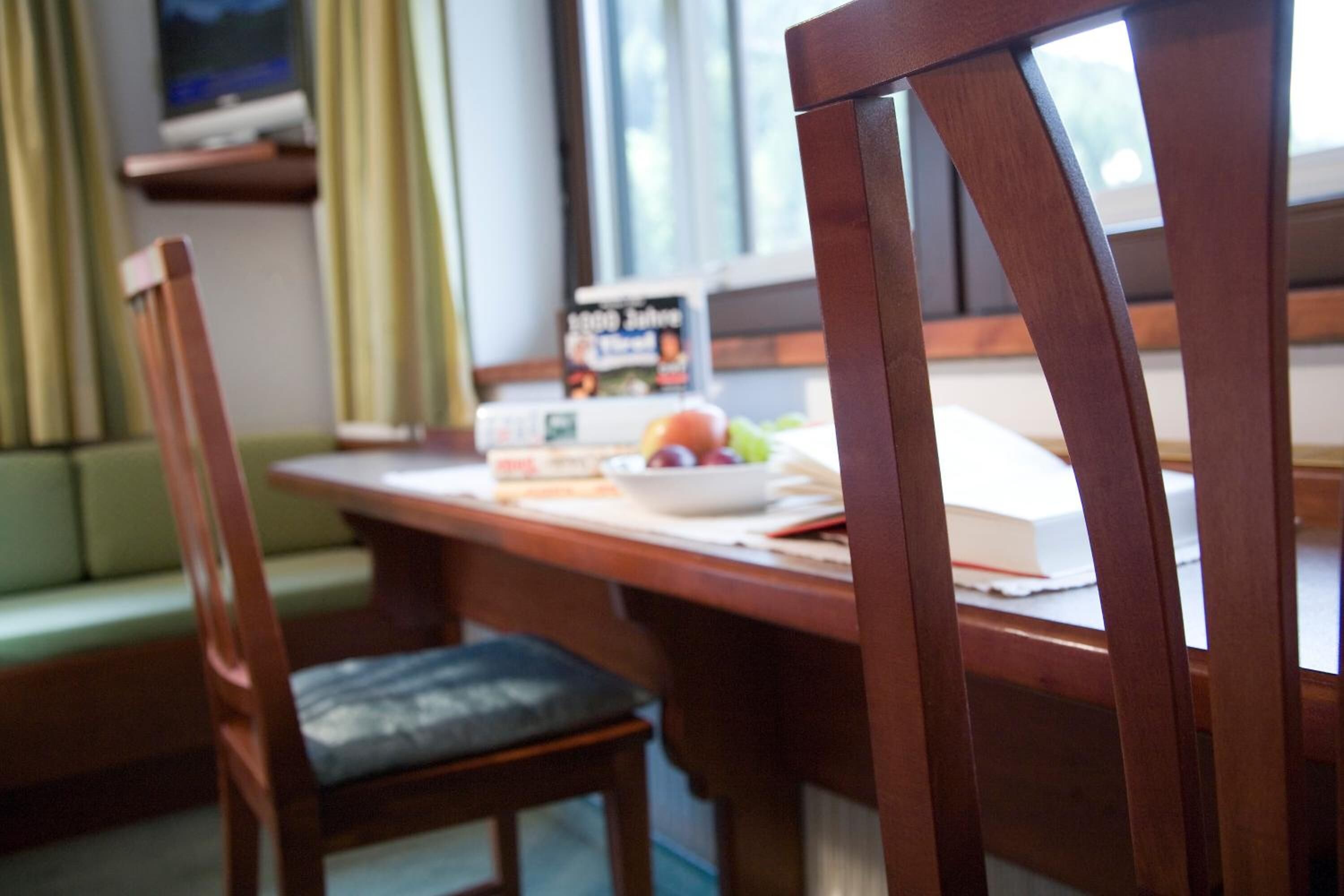 Una mesa de madera para comer con un bol de fruta y un libro.