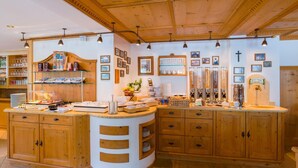 A kitchen with wooden cabinets, a central island, and various kitchen items. - Hotel Jakober (Tux)