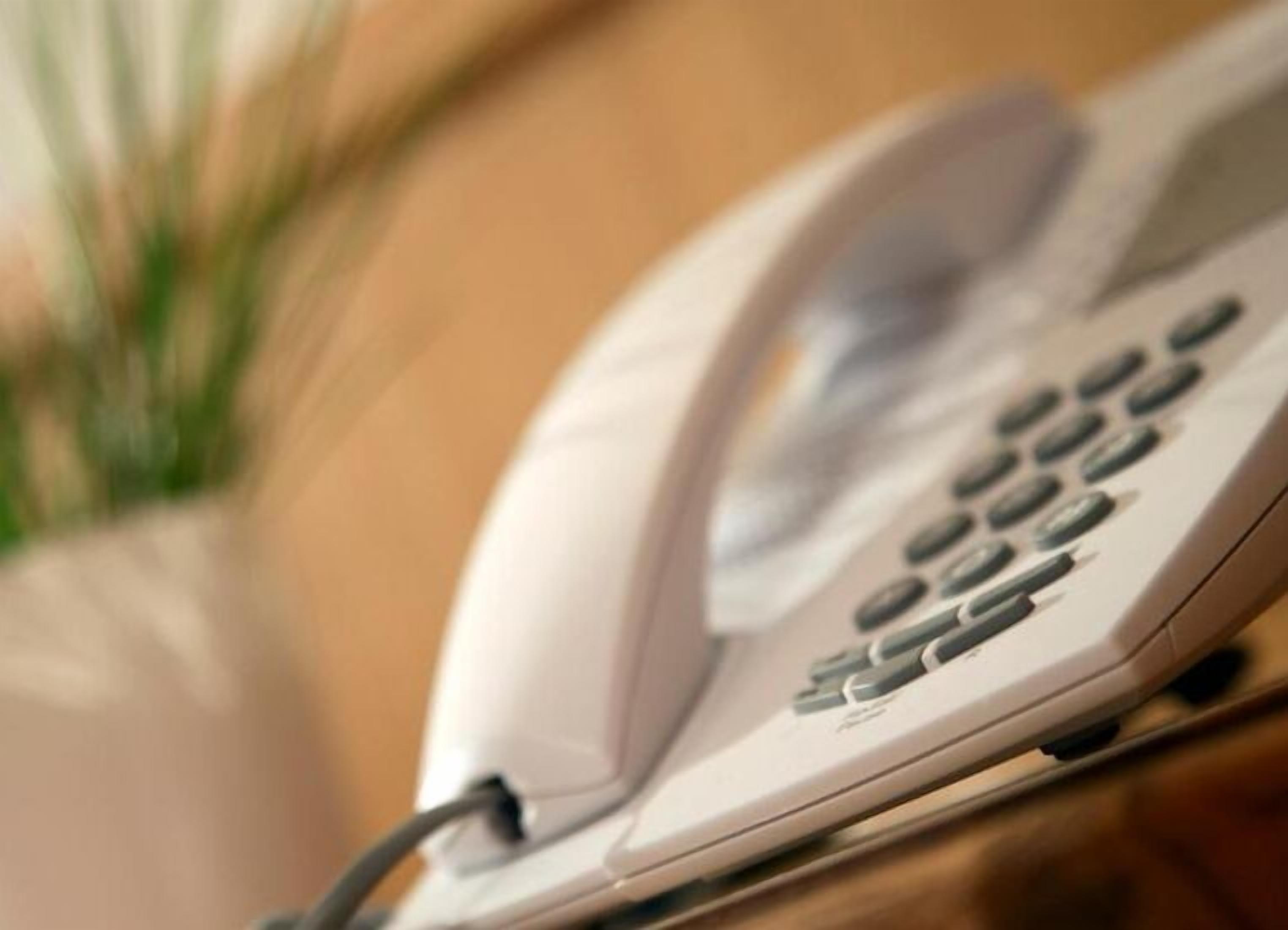 A white telephone on a wooden surface.