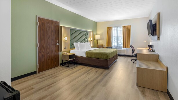 A hotel room with a bed, desk, chair, and a TV mounted on the wall. - Quality Inn & Suites Monterey I-40 (Monterey)