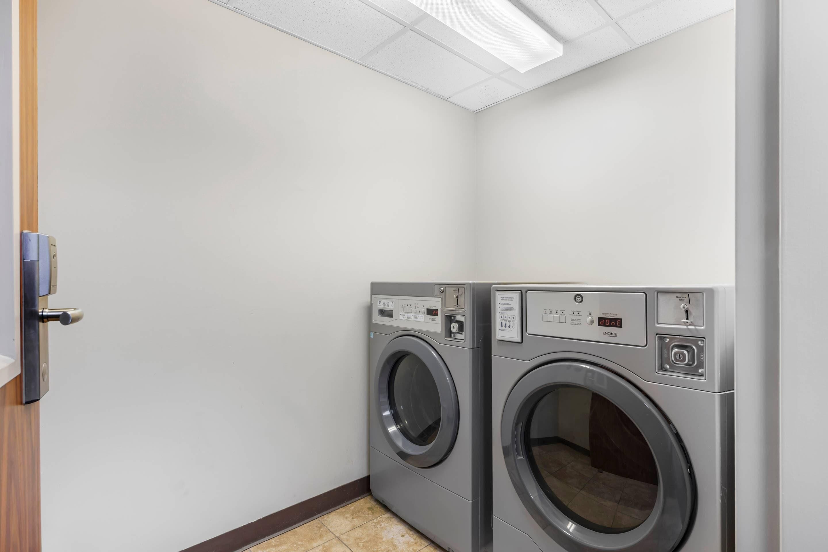 A laundry room with two front-loading washing machines and a door to the left.