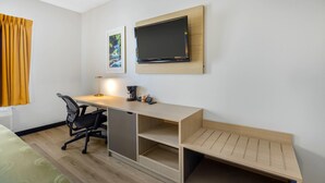 A hotel room with a desk, chair, TV, and artwork on the wall. - Quality Inn & Suites Monterey I-40 (Monterey)