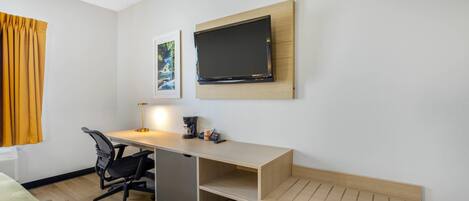 Habitación de hotel con escritorio, silla, televisor y una obra de arte en la pared.