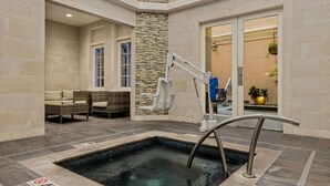 A spa area with a hot tub, seating, and a stone wall.