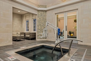 A spa area with a hot tub, seating, and a stone wall.