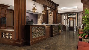 A lobby with a reception desk, wooden columns, and hanging lanterns.