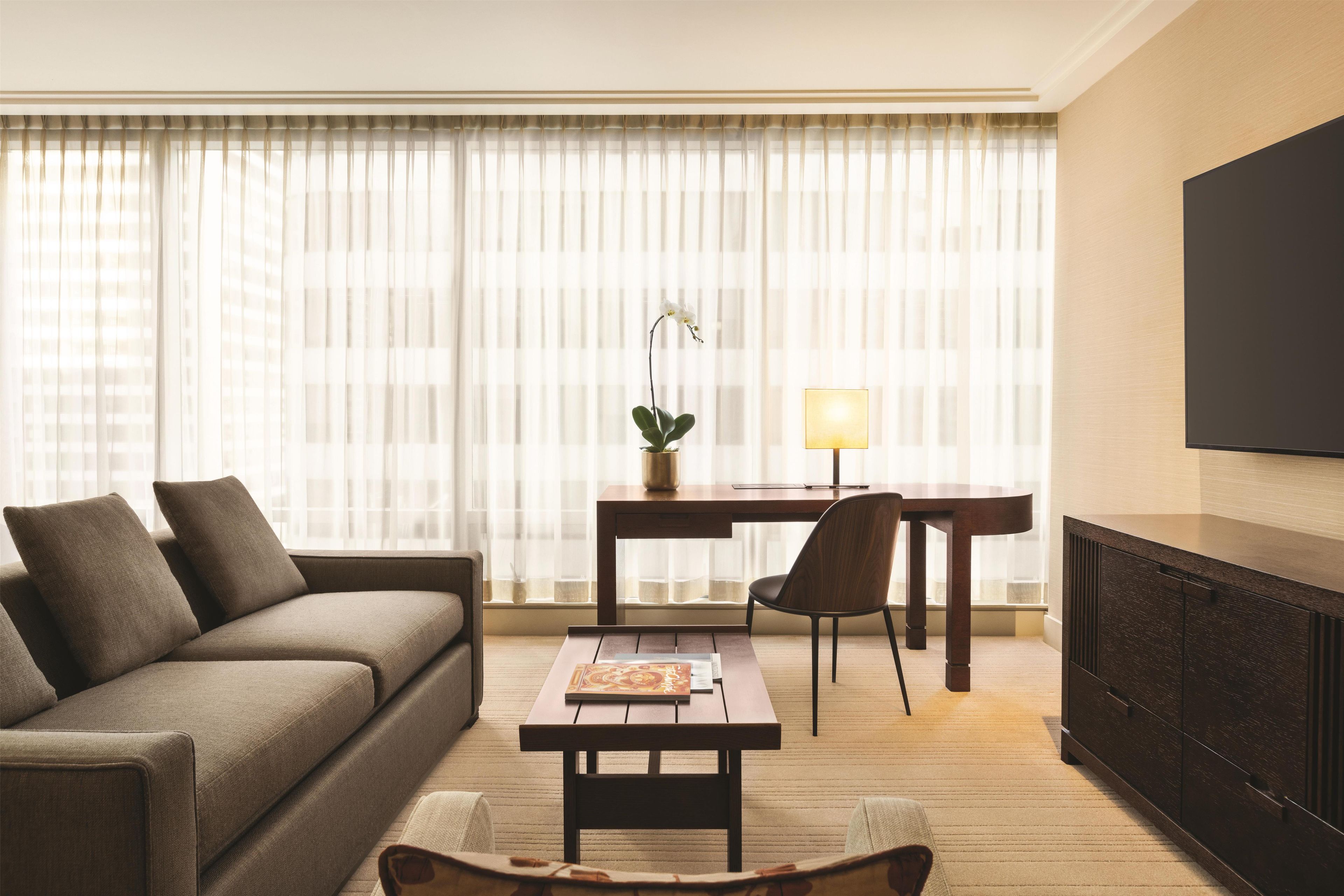 A modern living room with a sofa, a coffee table, a desk, and a TV.