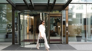 A modern hotel entrance with a revolving door, glass facade, and a visible '1128' sign.