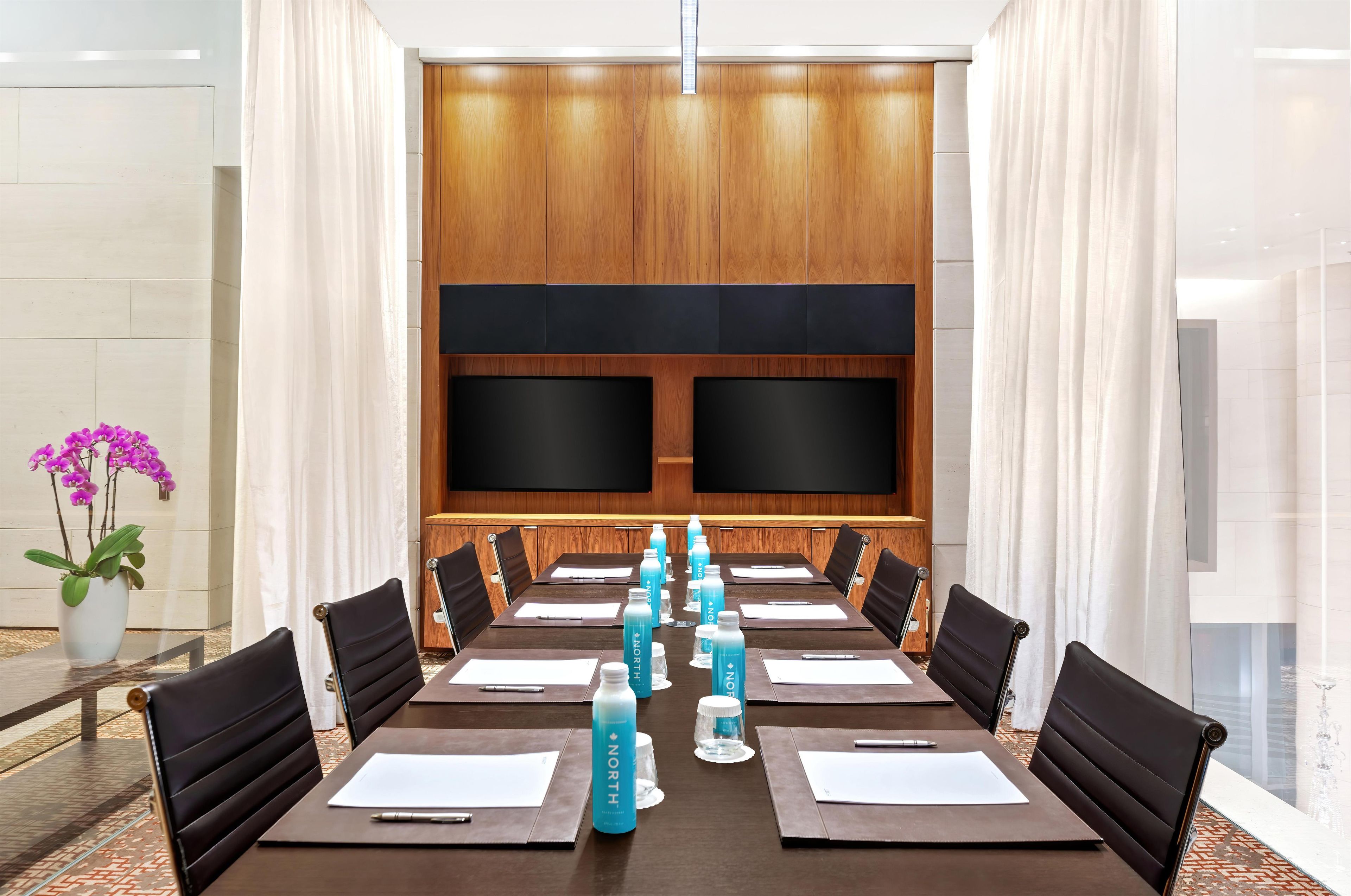 A conference room with a long table, black chairs, and blue water bottles.
