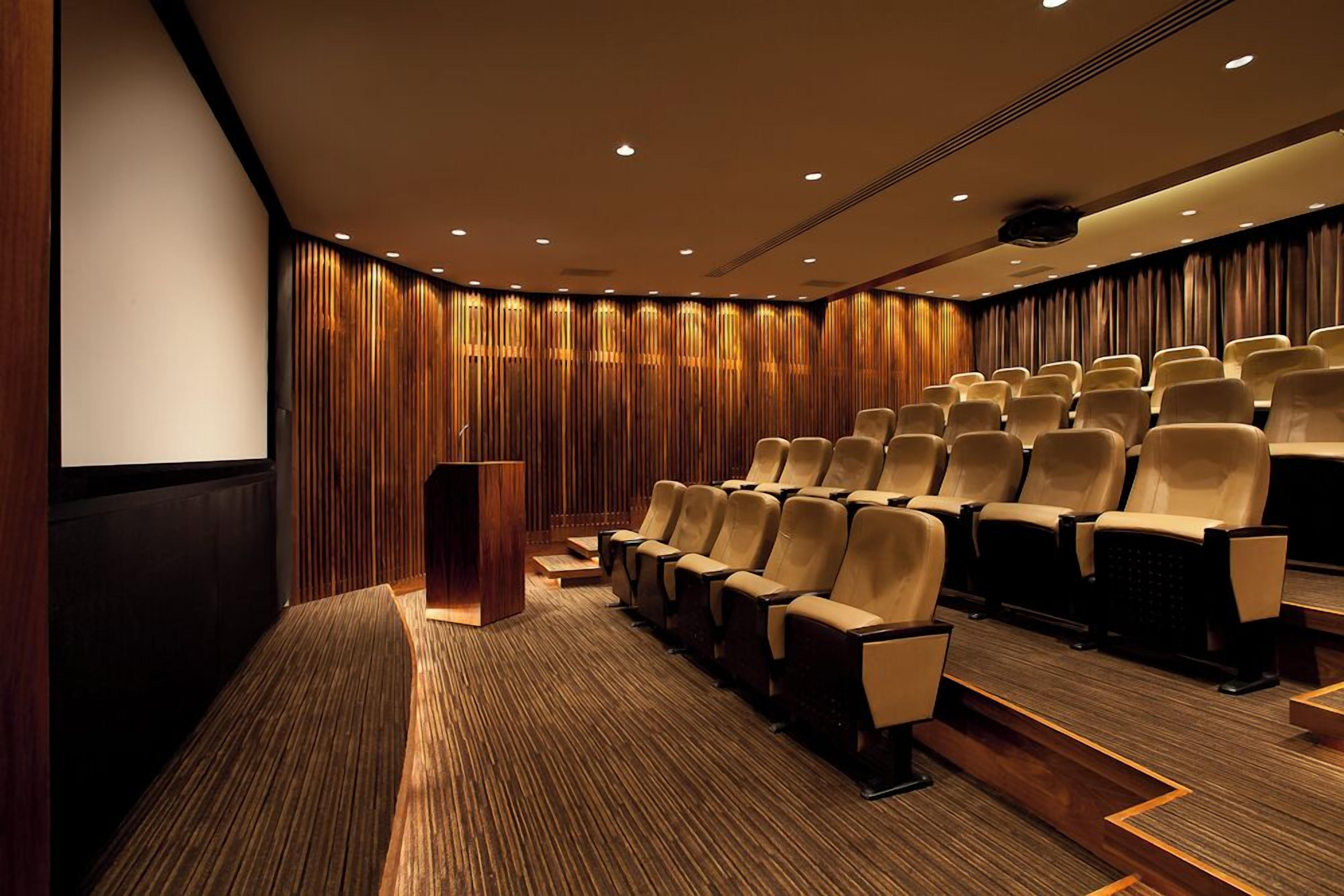 A cinema with rows of seats, a podium, and a large screen.