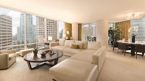 A modern living room with a large sofa, a coffee table, and a dining area with a chandelier.