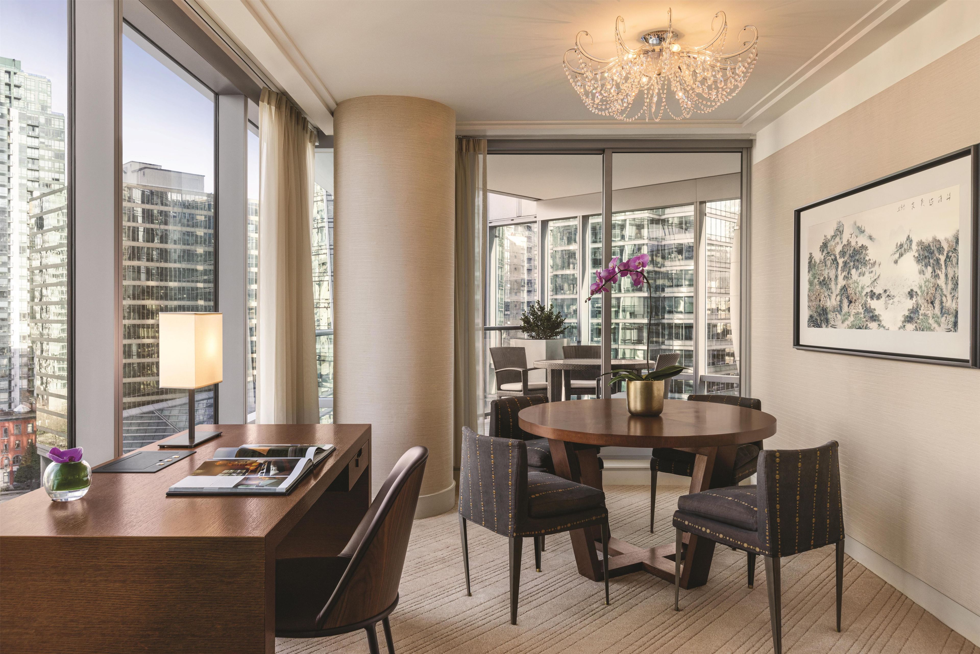A modern dining area with a round table, chairs, and a chandelier.