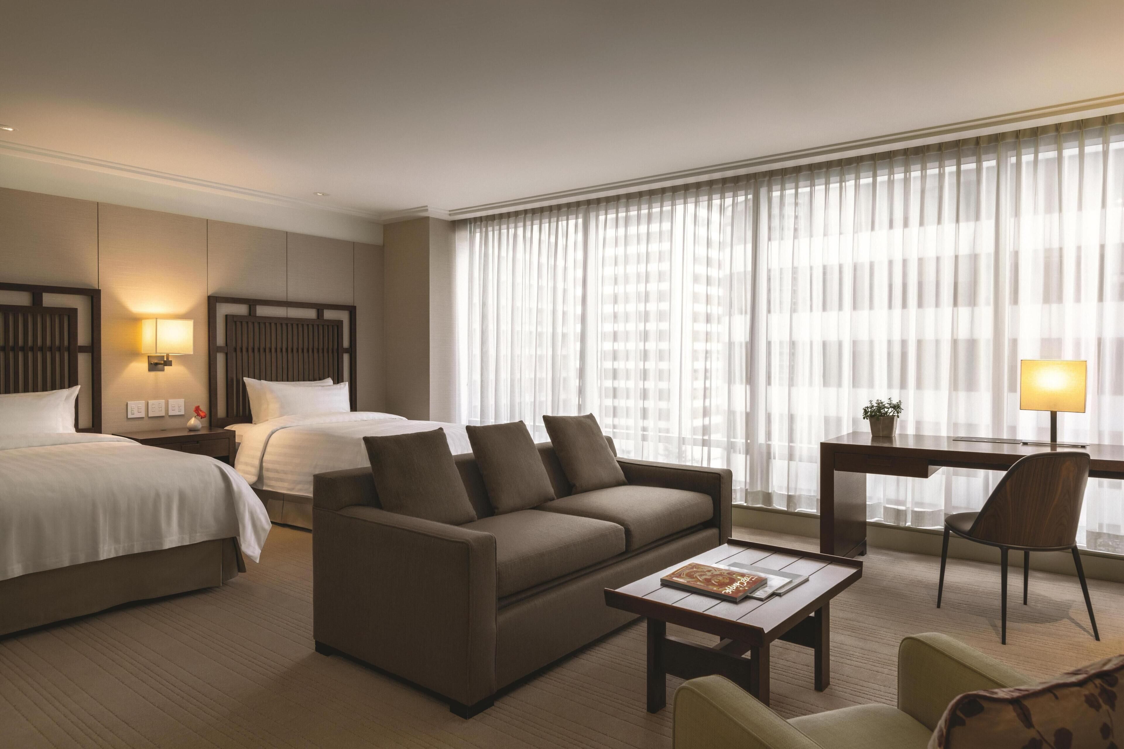 Habitación de hotel con cama, sofá, escritorio y una silla.